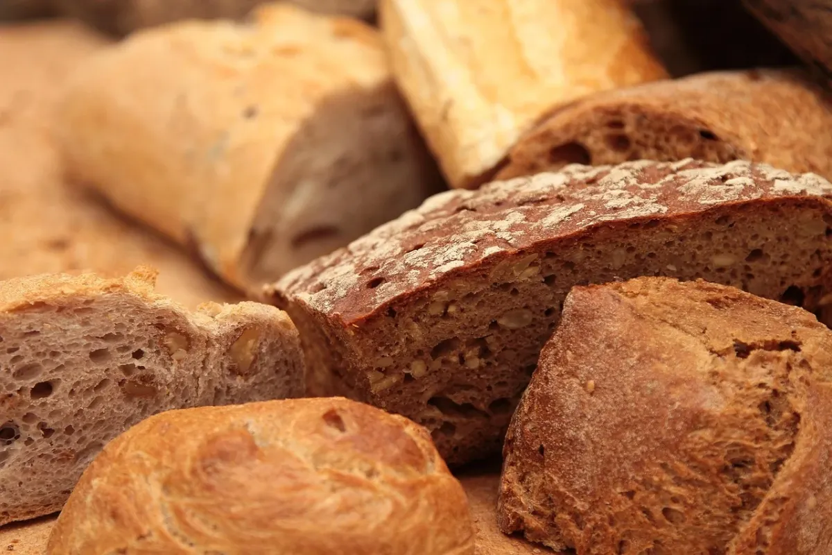 Świeżo upieczony chleb rzemieślnicowy leżący na drewnianym stole, podkreślający jakość i naturalność wypieków.